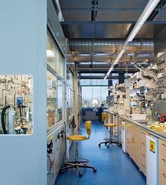 an industrial lab with lots of equipment on the walls and floor, as well as yellow stools