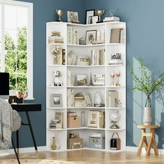 a living room with blue walls and white shelving unit in the corner next to a window