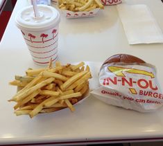 a table topped with two baskets of fries and a hamburger next to a cup of drink