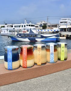 five jars filled with different types of food sitting on a ledge next to the water