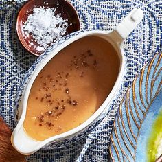 a bowl filled with sauce on top of a blue and white cloth next to two spoons