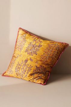 a yellow and red pillow sitting on top of a white floor next to a wall