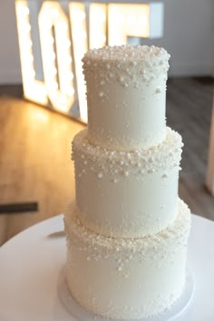 a three tiered white cake sitting on top of a table