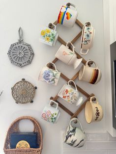 there are many cups and teapots hanging on the wall next to each other