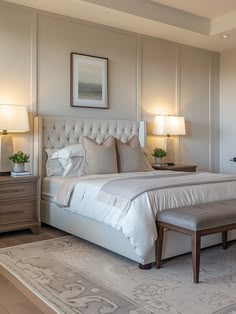 a large white bed sitting in a bedroom next to two lamps and a rug on top of a hard wood floor