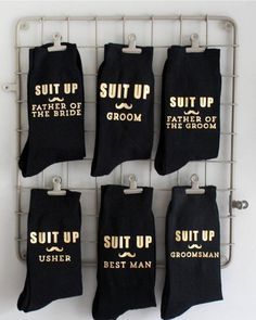 six pairs of grooms socks hanging on a rack with the words suit up, father of the groom and best man