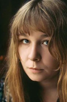 a close up of a person with long hair and blue eyes looking at the camera