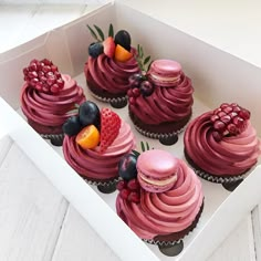 the cupcakes are decorated with pink icing and fruit on top, along with berries