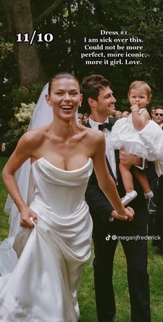 a woman in a wedding dress walking next to a man with a baby on her lap