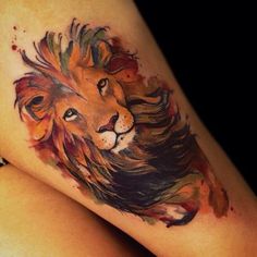 a watercolor tattoo of a lion on the thigh