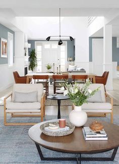 a living room filled with furniture next to a dining room table and chairs on top of a blue rug