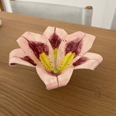 a pink and yellow flower sitting on top of a wooden table