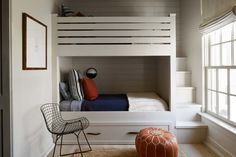 a white bunk bed sitting under a window next to a chair