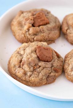 chocolate chip cookies on a white plate on a blue tablecloth, ready to be eaten