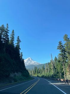 an empty road with trees and mountains in the background