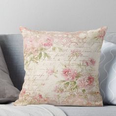 a pillow with pink roses on it sitting on top of a couch next to pillows