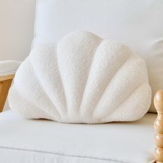 a white pillow sitting on top of a white couch next to a wooden table and chair