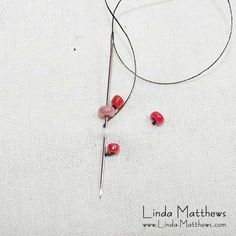 a pair of scissors and some red beads on a white surface with text overlay that reads, linda mathews