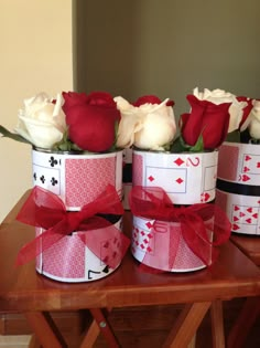 four roses are sitting in the center of three boxes with cards and bows on them