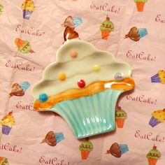 there is a cupcake shaped cookie on top of the cake paper sheeted tablecloth