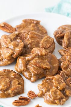 there are some cookies covered in caramel on a white plate with pecans around it