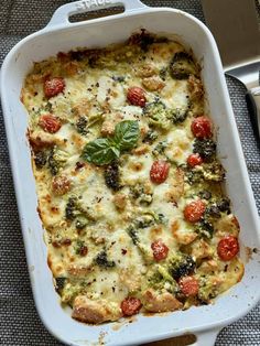 a casserole dish with tomatoes, broccoli and cheese in it on a table