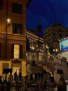 people are walking up and down the steps in front of an outdoor theater at night