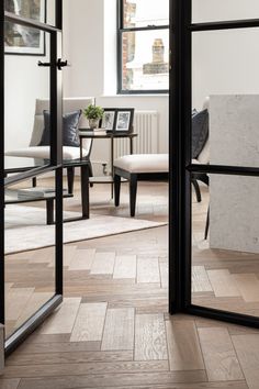 an open glass door leading to a living room with chairs and tables in the background