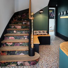 a stair case with flowers on it next to a wooden table and bench in front of the stairs