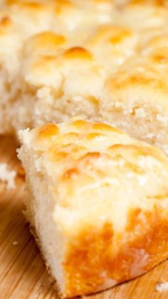 a piece of cheese bread sitting on top of a wooden cutting board