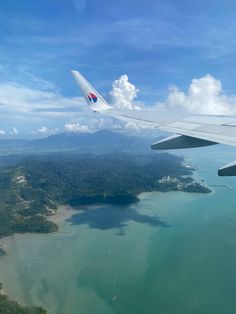 an airplane wing flying over the ocean and land