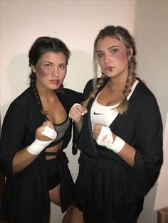 two beautiful women standing next to each other wearing boxing gloves and holding their hands together