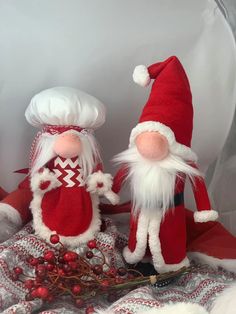 two red and white christmas gnomes sitting next to each other on a table cloth