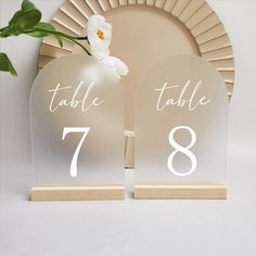 the table numbers are placed next to each other on wooden bases, with a white flower in between them