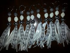 several key chains with white tassels and silver balls on them are lined up against a wooden table