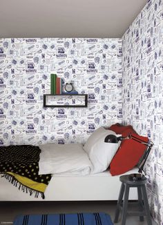 a small bedroom with blue and white wallpaper on the walls, along with a bed