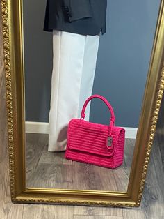 a pink purse sitting in front of a mirror