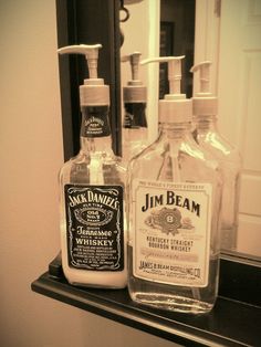 two bottles of jack daniels whiskey sitting on a counter in front of a bathroom mirror