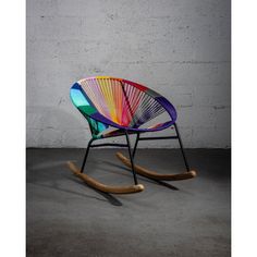 a multicolored rocking chair sitting in front of a white brick wall