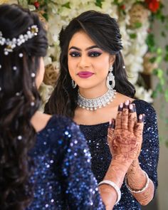 a woman in a blue dress is holding her hands out to another woman wearing a tiara