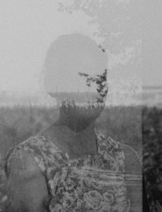 a black and white photo of a man's face in the middle of a field