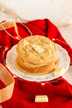 two cookies are stacked on a plate next to a red and white cloth with gold ribbon