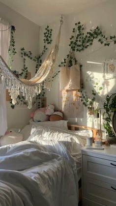 an unmade bed with white sheets and hanging plants