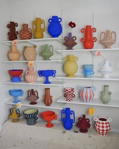 there are many different vases on the shelves