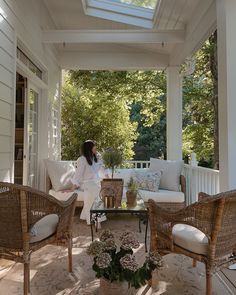 a woman sitting on a porch with wicker furniture