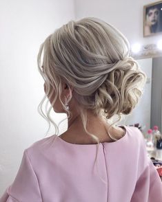 a woman is getting her hair done in front of a mirror with lights on the wall