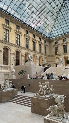 the inside of a building with many statues and people walking around in front of it