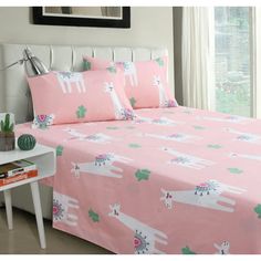 a bed covered in pink sheets with white llamas and cactuses on them