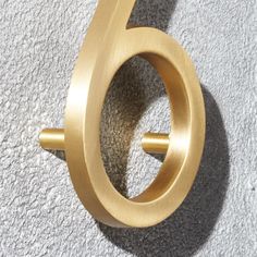 the number six is shown in gold on a white wall with grey concrete flooring