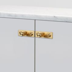 two brass handles on a white cabinet with marble top